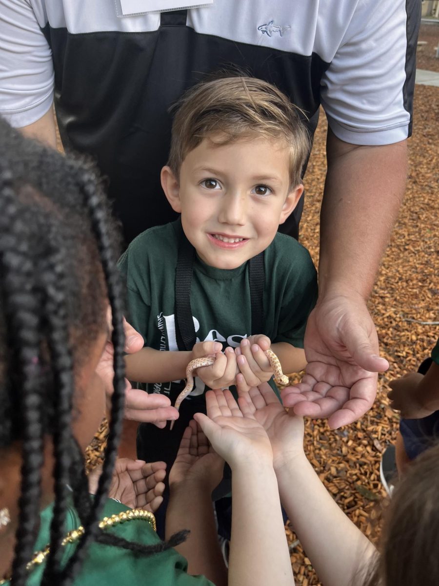 Lower schooler smiles while showing off a pet snake.