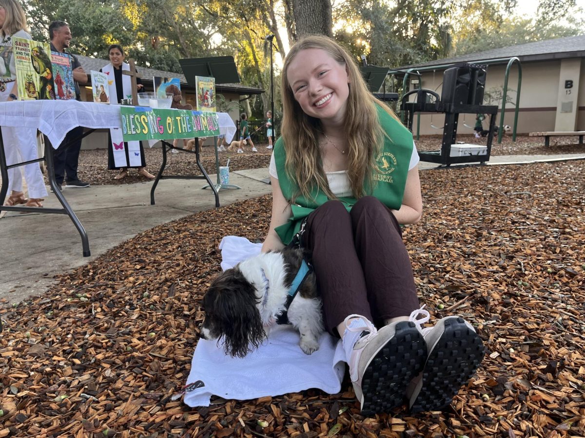 Student chaplain Ella Ziegler flashes a smile while petting a dog.