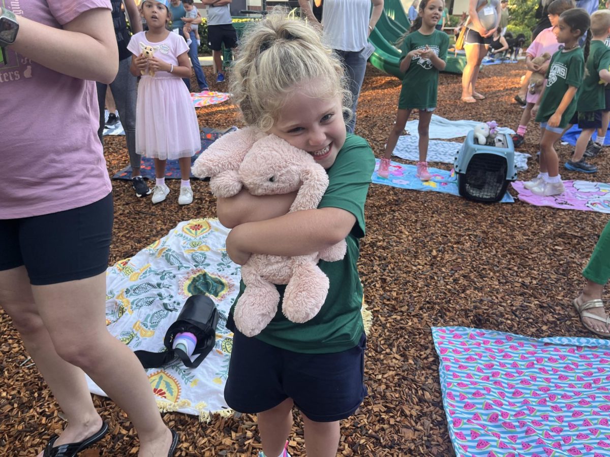 Lower school falcon hugs her stuffed bunny animal eagerly.