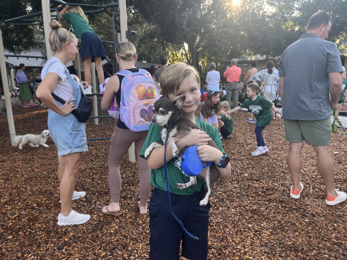 Lower schooler smiles big while holding his pet dog.