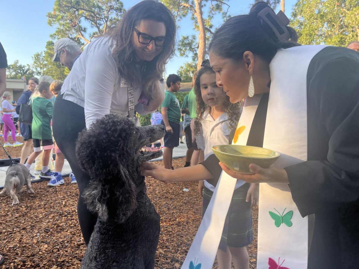 School chaplain Rev. Cori blesses an adorable poodle.