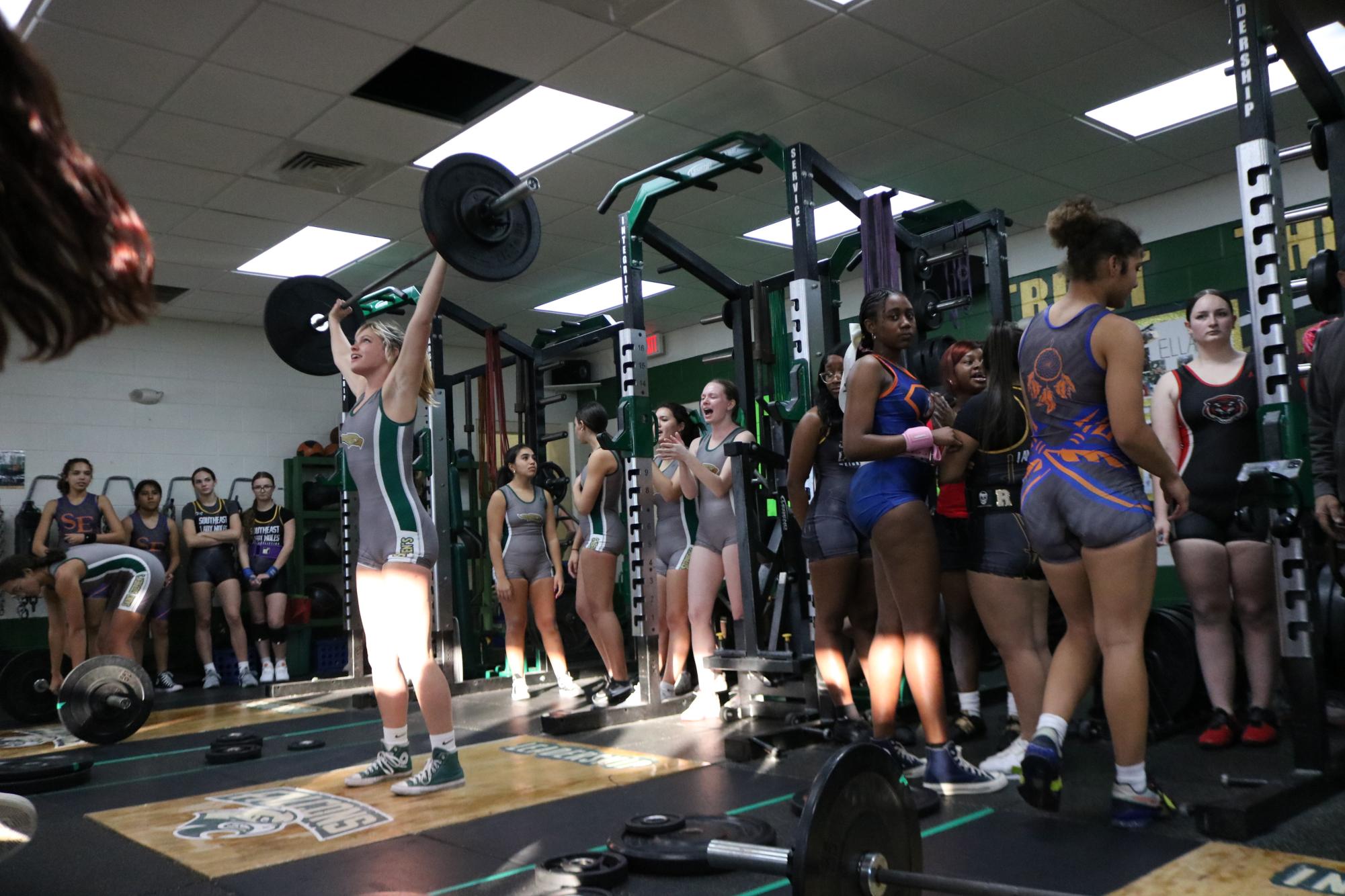 Teammates look on as Betsy Neal completes a snatch. 