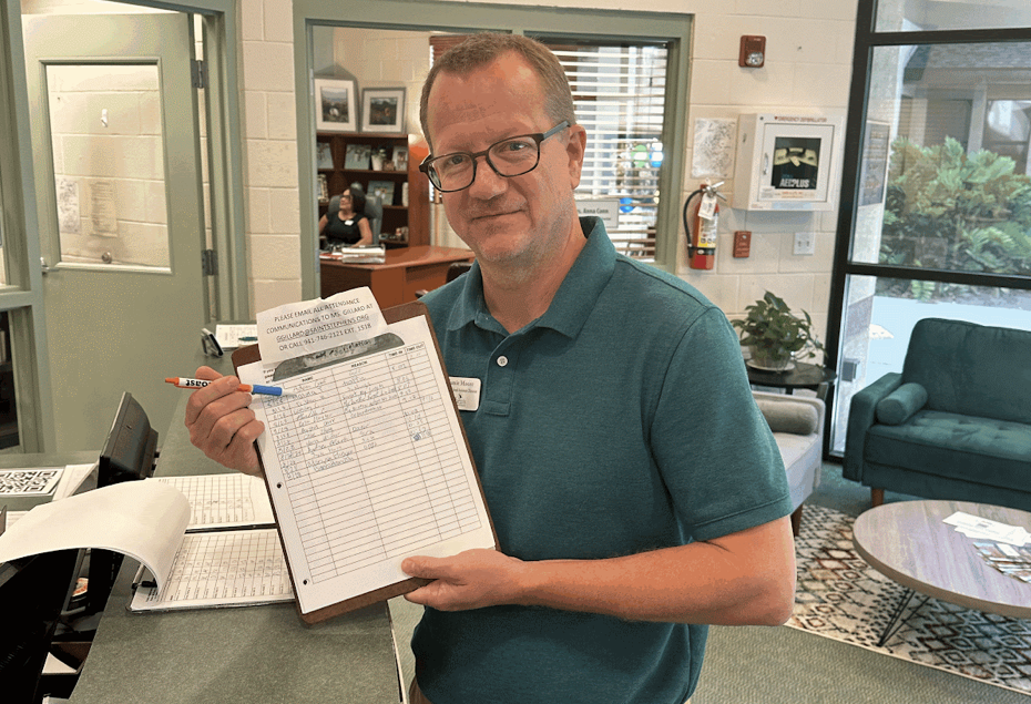 Mr. Moore displaying the sign in/out sheet and counting off the number of tardys.